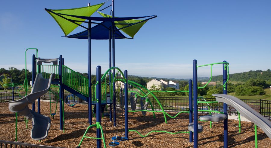 A vibrant playground with blue and green play structures set against a clear blue sky.